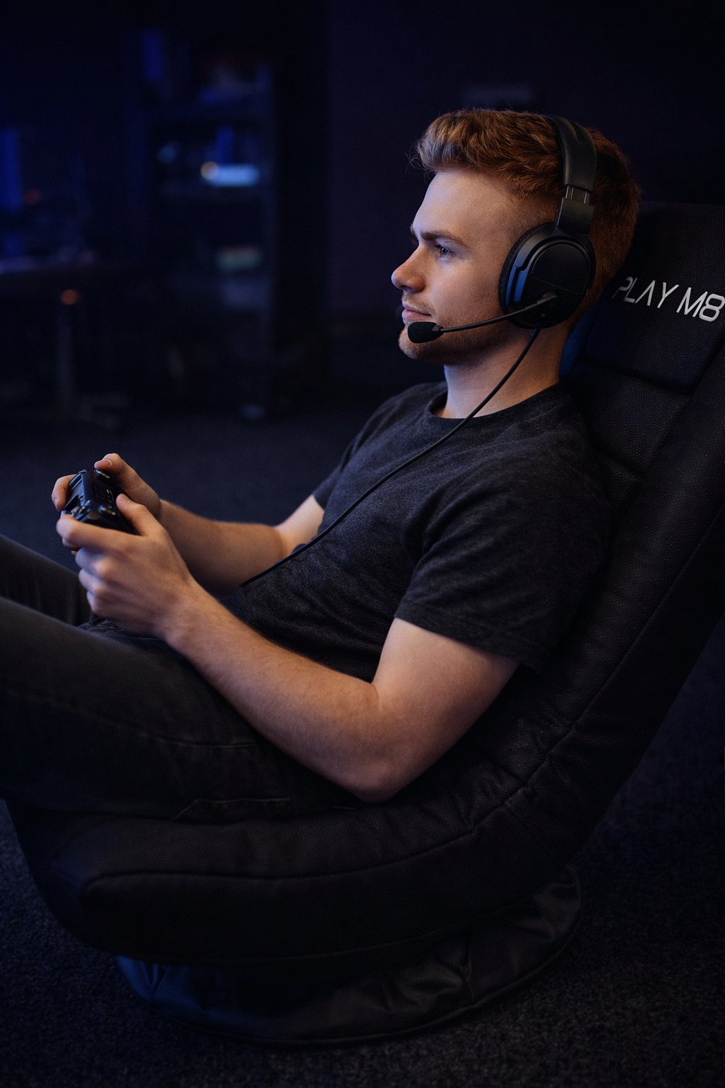 Focused gamer sitting in Play M8 console gaming chair with headset and controller